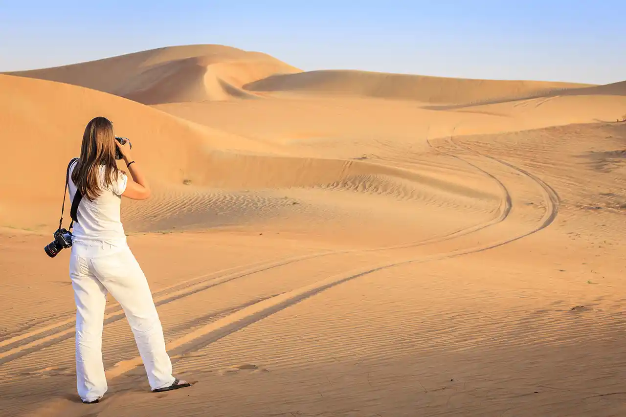 Tourist capturing photos of desert dunes during a peaceful morning safari in Dubai