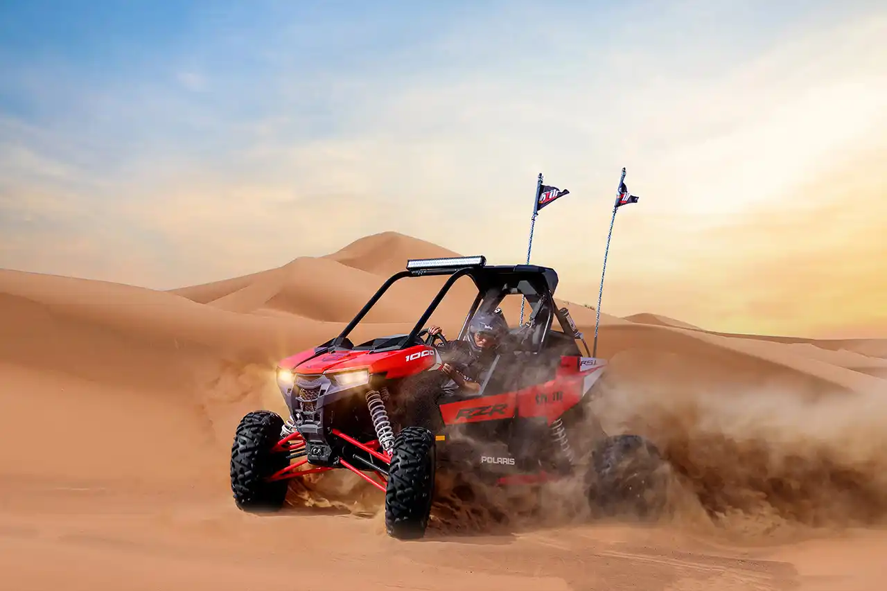 Tourist riding a dune buggy through golden sands on a morning desert safari in Dubai