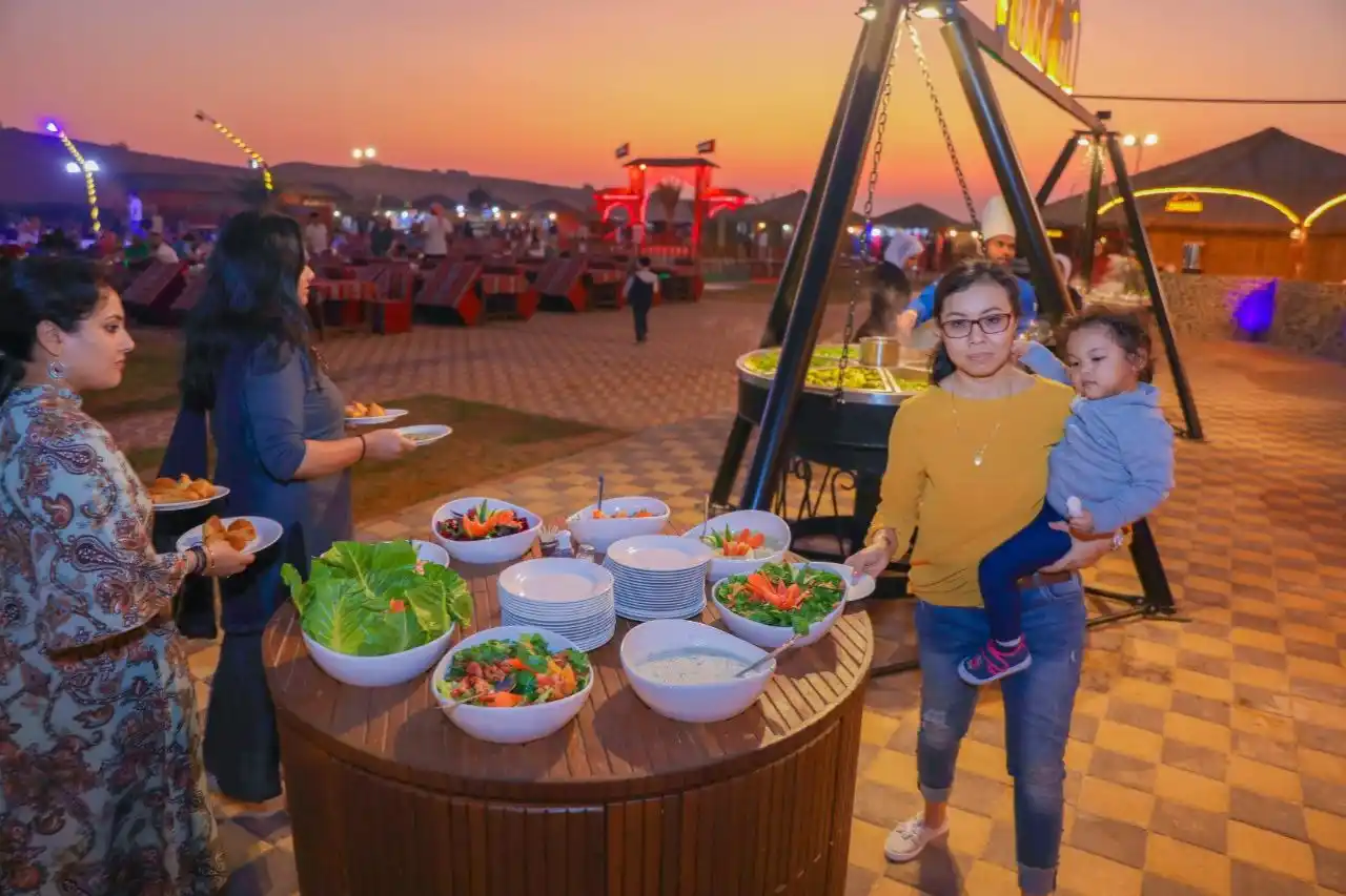 Family enjoying a buffet dinner at a desert safari camp in Dubai during sunset