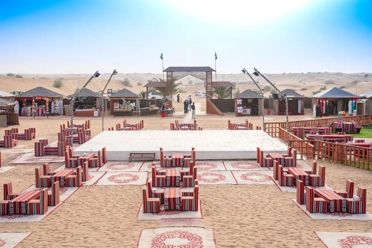 Evening view of Dubai desert safari camp with traditional setup and guests dining