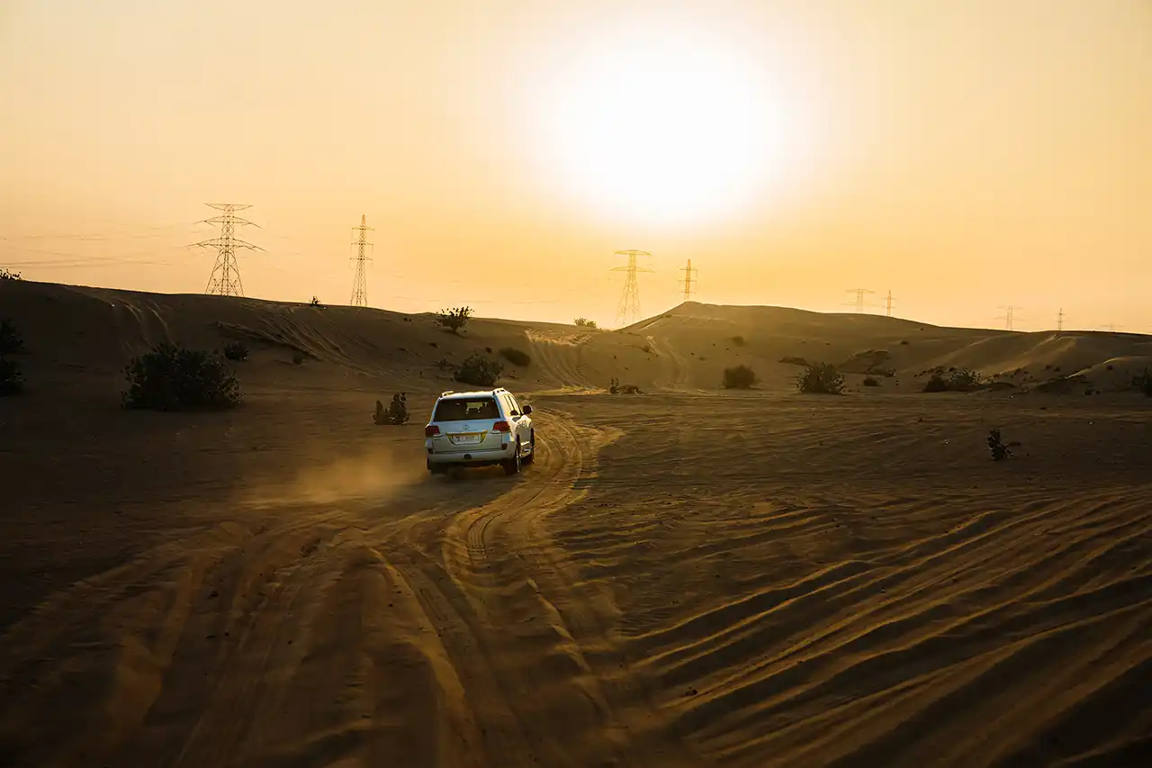 SUV driving through desert dunes during sunrise on a morning desert safari in Dubai