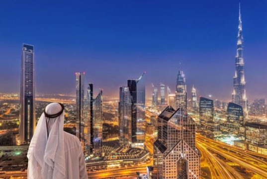 Arabian man watching night cityscape of Dubai.